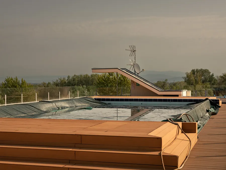 Covered rooftop pool with wooden decking and a diving board