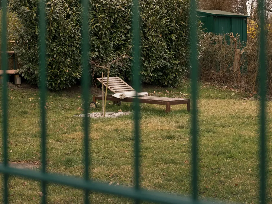Sun lounger in a garden seen through a green fence