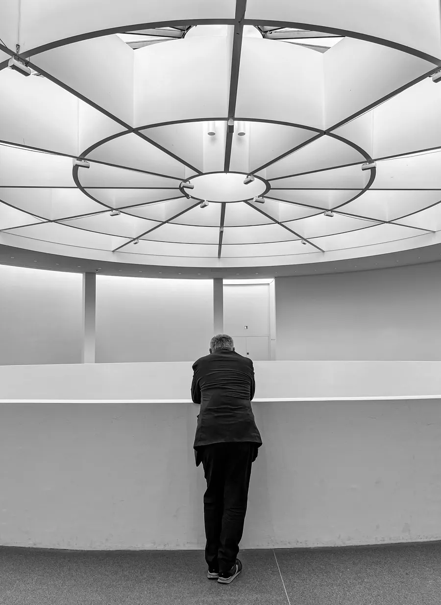 Man leaning on the balustrade beneath a domed skylight