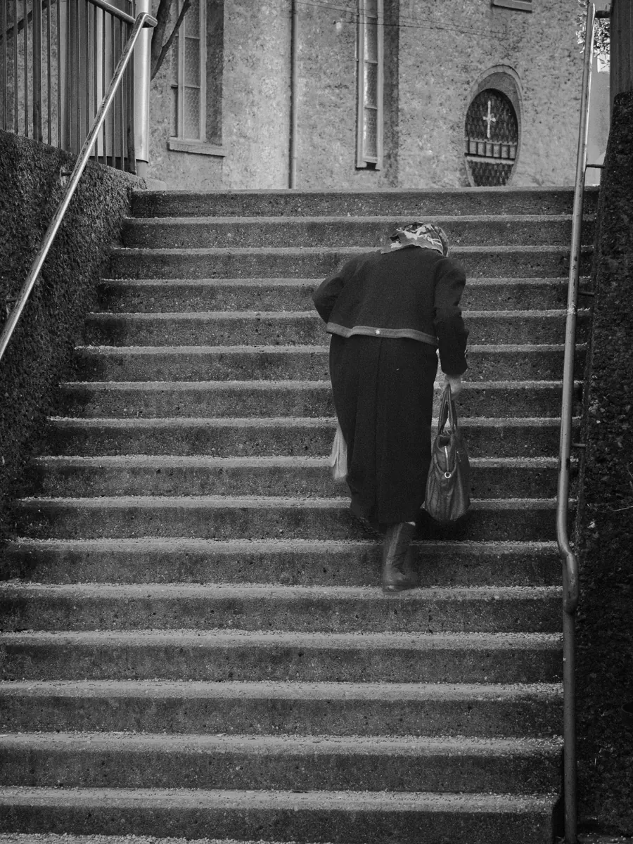 Elderly woman with a bag climbing church steps