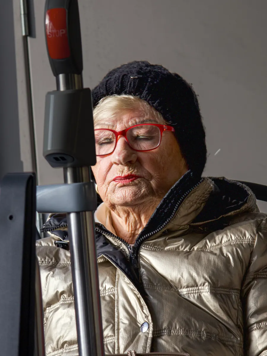 Elderly woman with red glasses in a bus