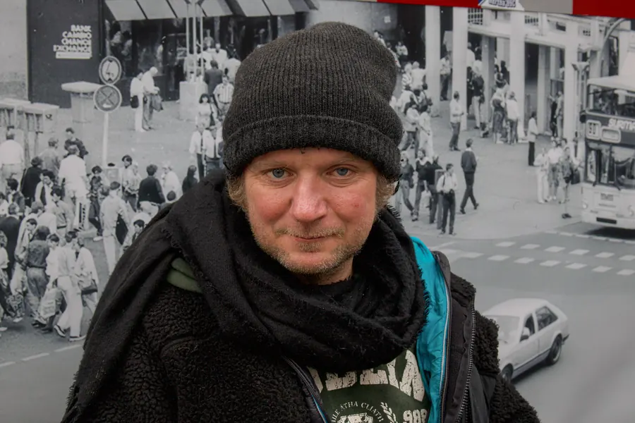 Man in a black beanie in front of a historic street photograph