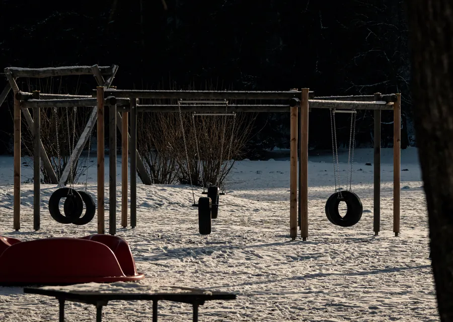 Tyre swings on a snowy playground at the forest edge