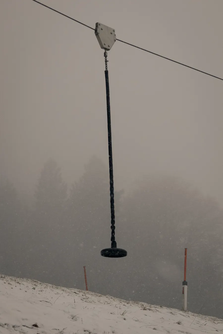 Zip line seat hanging in fog above the snow